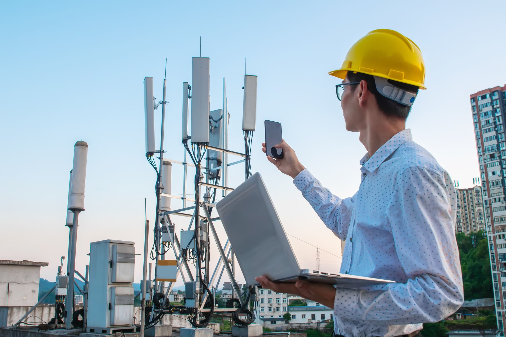 Engineer working on a laptop and phone,Checking the communications tower